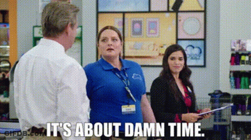 A Woman In A Blue Shirt Is Talking To A Man In A Store . GIF