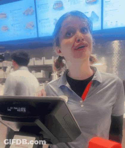 A Woman In A Blue Shirt Stands Behind A Cash Register That Says Gift Cards GIF
