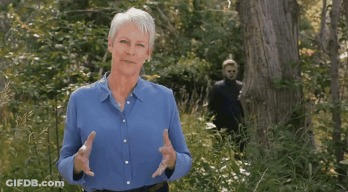 A Woman In A Blue Shirt Stands In A Forest GIF