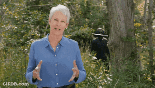 A Woman In A Blue Shirt Stands In The Woods GIF