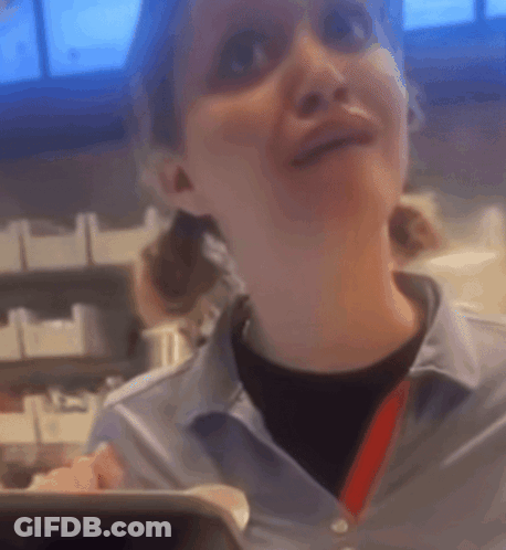 A Woman In A Blue Shirt With A Red Lanyard Around Her Neck Is Smiling GIF