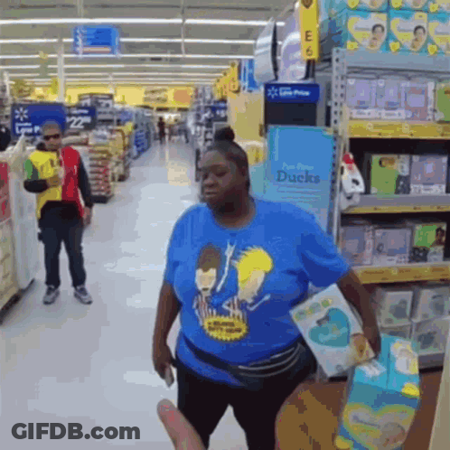 A Woman In A Blue Shirt With Beavis And Butthead On It Is Standing In A Store GIF