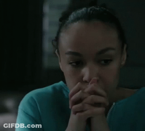 A Woman In A Blue Shirt With Her Hands Folded In Front Of Her Face GIF