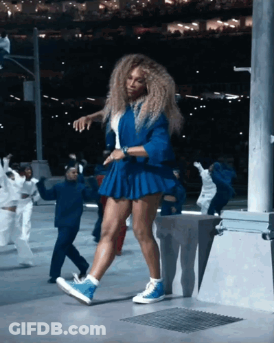 A Woman In A Blue Skirt Is Dancing With A Group Of People GIF