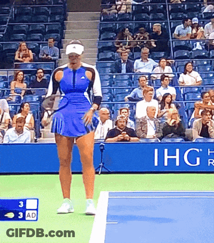 A Woman In A Blue Skirt Is Standing On A Tennis Court In Front Of An Ihg Sign GIF
