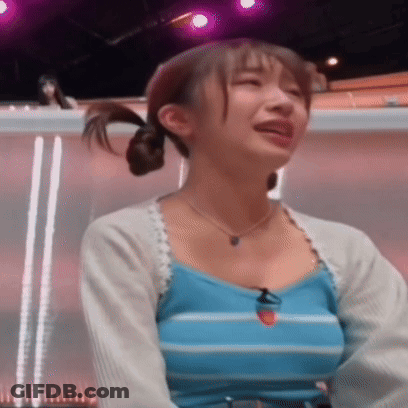 A Woman In A Blue Striped Tank Top Is Crying While Sitting In Front Of A Purple Light . GIF