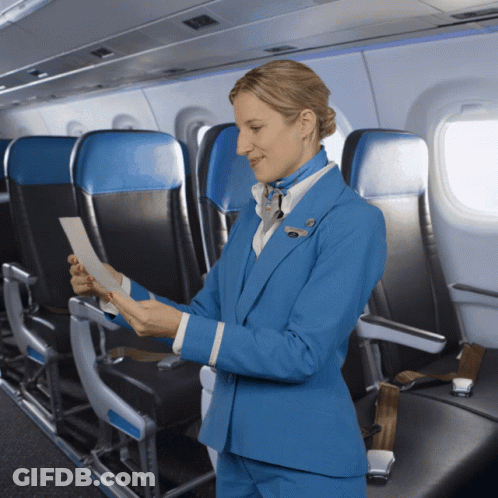 A Woman In A Blue Suit Is Looking At A Piece Of Paper On A Plane GIF