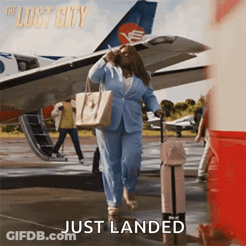 A Woman In A Blue Suit Is Walking Towards An Airplane With The Words Just Landed Below Her GIF