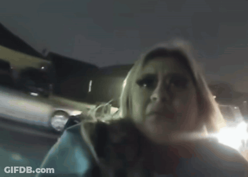 A Woman In A Blue Sweater Holds Her Hand To Her Head GIF