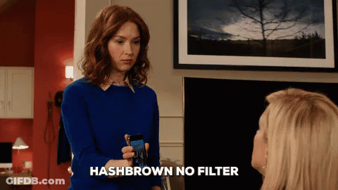 A Woman In A Blue Sweater Is Holding A Cell Phone With The Words Hashbrown No Filter Below Her GIF