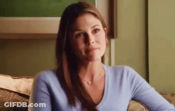 A Woman In A Blue Sweater Is Sitting On A Couch . GIF