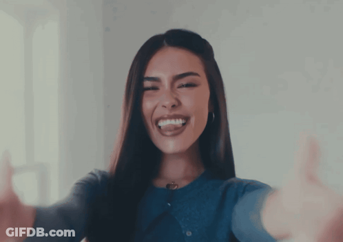 A Woman In A Blue Sweater Is Smiling And Giving A Thumbs Up GIF