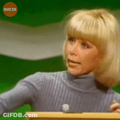 A Woman In A Blue Sweater Is Standing In Front Of A Green Screen With Buzzr Written On It GIF