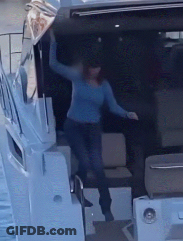 A Woman In A Blue Sweater Stands On A Boat GIF