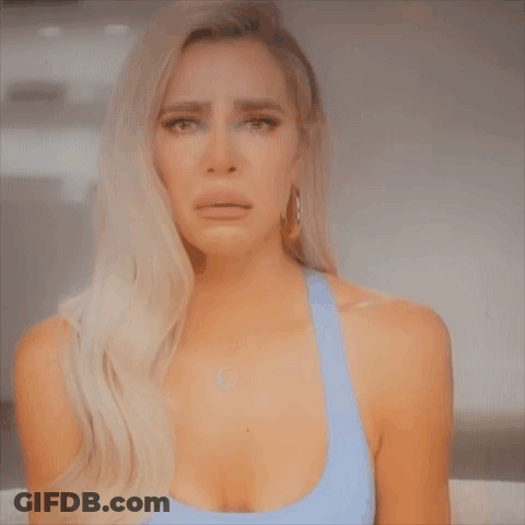 A Woman In A Blue Tank Top Is Crying And Making A Face . GIF