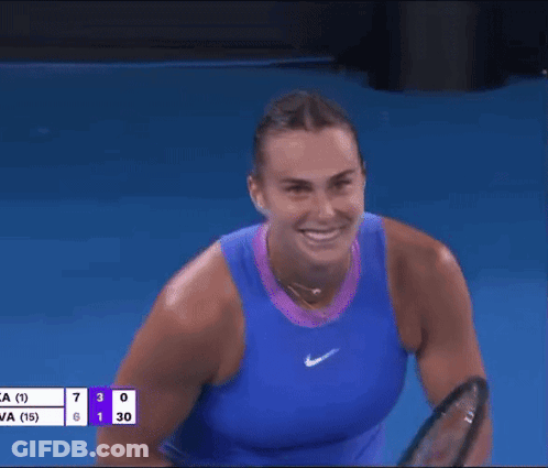 A Woman In A Blue Tank Top Is Holding A Tennis Racquet In Her Hand . GIF