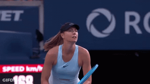 A Woman In A Blue Tank Top Is Holding A Tennis Racquet On A Court . GIF