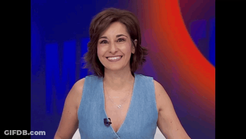 A Woman In A Blue Tank Top Is Smiling And Wearing A Microphone . GIF
