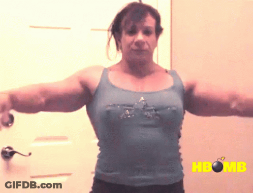 A Woman In A Blue Tank Top Is Standing In Front Of A Door With The Word Hbomb On The Bottom GIF