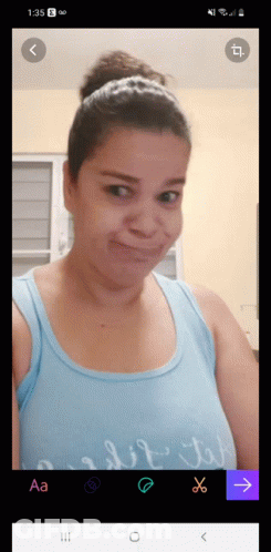 A Woman In A Blue Tank Top Is Taking A Picture Of Herself GIF