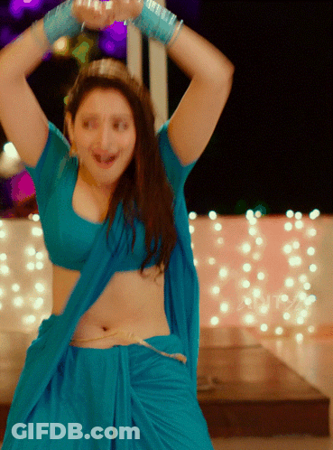 A Woman In A Blue Top And Skirt Is Dancing With Her Arms In The Air GIF