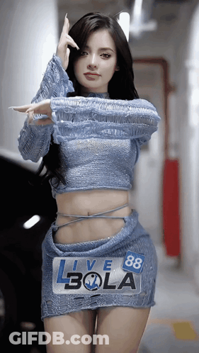 A Woman In A Blue Top And Skirt Is Standing In Front Of A Sign That Says Live 88 Bola GIF