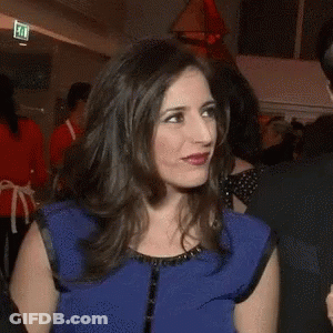 A Woman In A Blue Top Is Holding A Microphone That Says Oi GIF