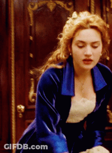 A Woman In A Blue Velvet Dress Is Standing In Front Of A Door GIF
