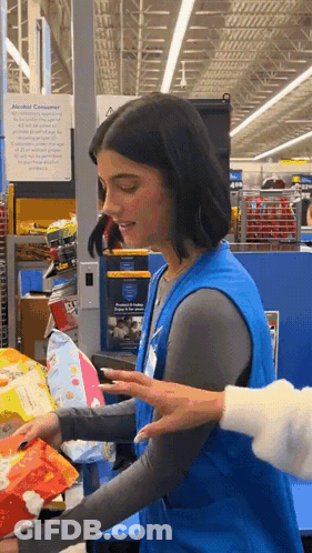 A Woman In A Blue Vest Holds A Bag Of Chips In A Store GIF