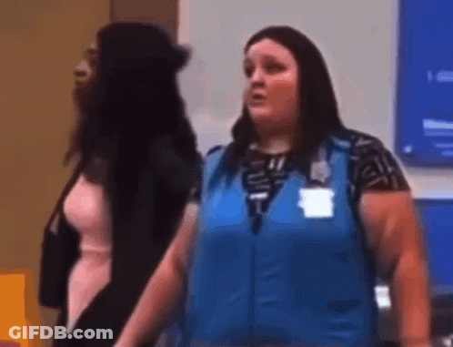 A Woman In A Blue Vest Is Standing Next To Another Woman In A Room . GIF