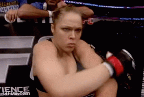 A Woman In A Boxing Ring With A Sign That Says Ultimate Fighters Championship In The Background GIF