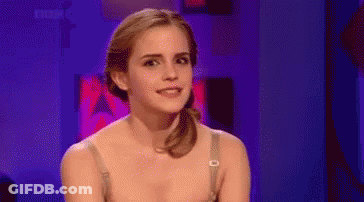A Woman In A Bra Is Sitting In Front Of A Purple Background And Smiling . GIF