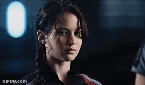 A Woman In A Braided Ponytail Looks At The Camera GIF