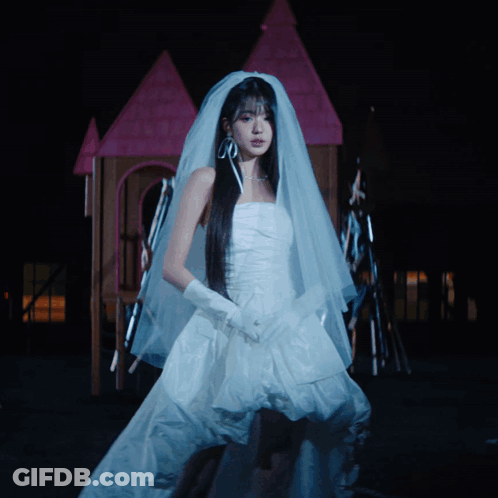 A Woman In A Bride 'S Dress Is Standing In Front Of A Fire GIF