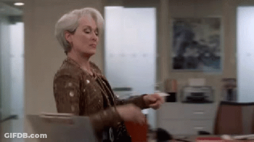 A Woman In A Brown Jacket Is Holding A Piece Of Paper In Her Hand . GIF