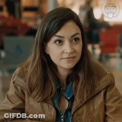 A Woman In A Brown Jacket Is Sitting At A Table In A Restaurant . GIF