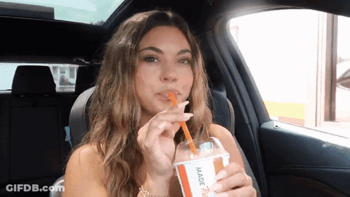 A Woman In A Car Drinking Through A Straw From A Cup That Says Made GIF