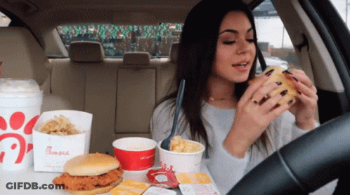A Woman In A Car Eating A Chicken Sandwich From A Chick-Fil-A Bag GIF