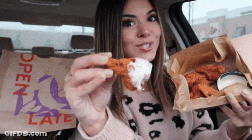 A Woman In A Car Eating Chicken Wings With A Bag That Says Open Late On It GIF