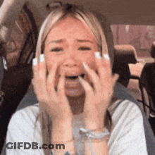 A Woman In A Car Is Covering Her Face With Her Hands GIF
