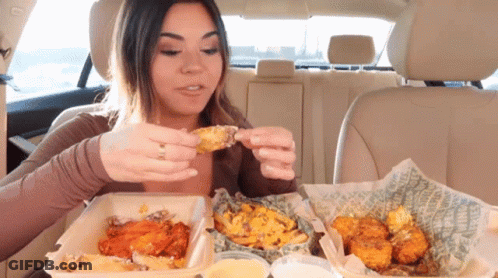 A Woman In A Car Is Eating Chicken Wings GIF