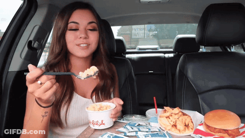 A Woman In A Car Is Eating Macaroni And Cheese From A Cup That Says Chick-Fil-A GIF