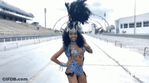 A Woman In A Carnival Costume Is Standing In Front Of A Stadium . GIF