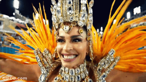 A Woman In A Carnival Costume With Feathers And Rhinestones Is Smiling . GIF