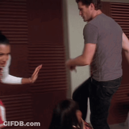 A Woman In A Cheerleader Outfit Is Standing Next To A Man In A Grey Shirt GIF
