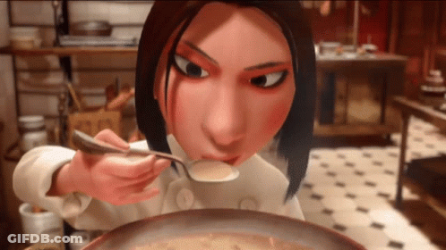 A Woman In A Chef 'S Uniform Is Eating Soup With A Spoon GIF