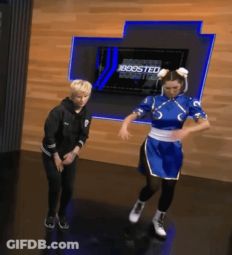 A Woman In A Chun Li Costume Is Dancing In Front Of A Wall That Says Boosted GIF