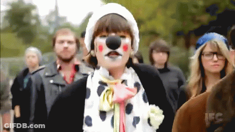 A Woman In A Clown Costume Is Standing In A Crowd GIF
