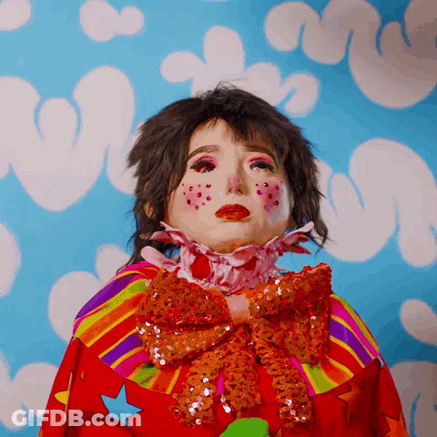 A Woman In A Clown Costume With A Rainbow Collar And Bow GIF