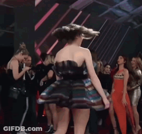 A Woman In A Colorful Dress Is Dancing In Front Of A Crowd Of People GIF
